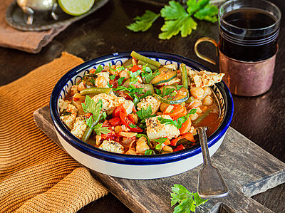 Tofustückchen mit buntem Gemüse in einer Schale mit Tischdekoration.