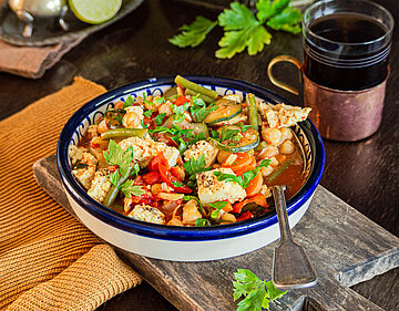 Tofustückchen mit buntem Gemüse in einer Schale mit Tischdekoration.