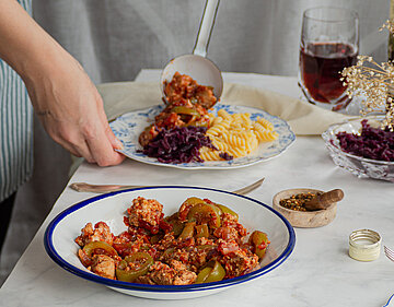 Tofu-Gulasch mit Nudeln auf Tellern auf einer Tischdecke mit Tischdekoration.