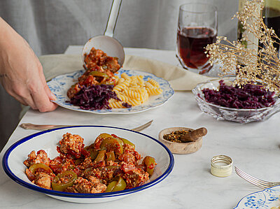 Tofu-Gulasch mit Nudeln auf Tellern auf einer Tischdecke mit Tischdekoration.
