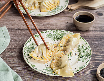 Gefüllte Nudeltaschen auf einem Teller mit Tischdekoration.