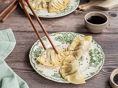 Gefüllte Nudeltaschen auf einem Teller mit Tischdekoration.