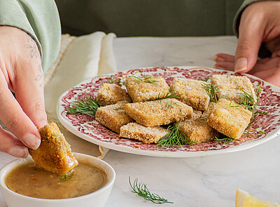 Gelbe Tofuwürfel auf einem Teller mit Zitrone und Gurke und Dekoration.