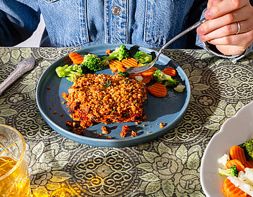 Schlemmerfilet Tofugehacktes an gemischetes Gemüse auf einem blauen Teller mit Tischdekoration.