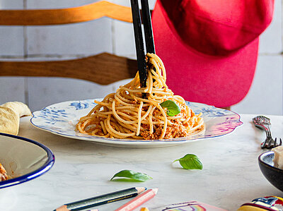 Spaghetti mit Tofu-Gehacktem auf einem Teller mit Dekoration.