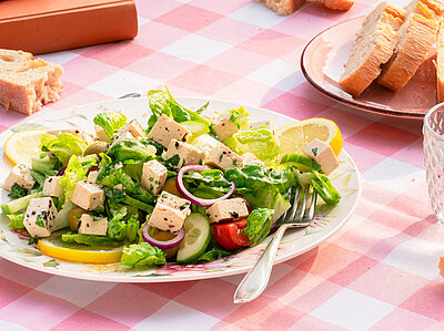 2 Teller mit Sojawürfeln auf Salat mit Zitrone und Brot mit Tischdekoration.
