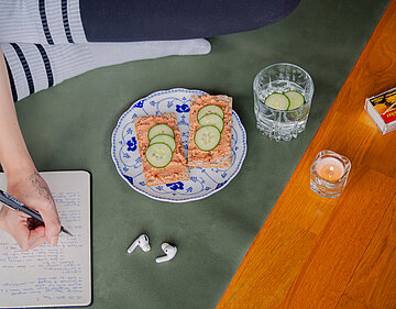 Knäckebrot mit Tofu-Tomaten-Creme Knäckebrotscheiben mit einer roten Creme und Gurkenscheiben auf einem Teller mit Dekoration.