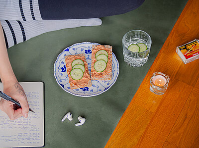 Knäckebrotscheiben mit einer roten Creme und Gurkenscheiben auf einem Teller mit Dekoration.