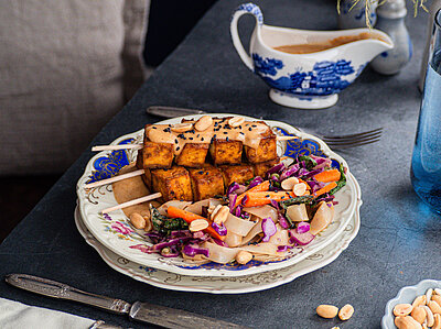 3 Tofuspieße mit Salat, Erdnüssen und Dip mit Tischdekoration.