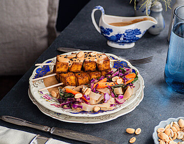 3 Tofuspieße mit Salat, Erdnüssen und Dip mit Tischdekoration.
