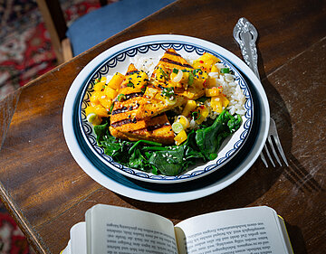 Indischer Tofu mit Mango Chutney Gegrillter Tofu auf Salat und Reis und Mango in einem Teller mit Tischdekoration.