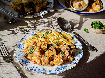 Tofu Geschnetzeltes mit Pilzen und Nudeln auf einem Teller mit Tischdekoration.