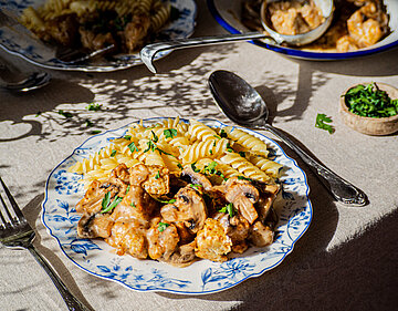 Tofu Geschnetzeltes mit Pilzen und Nudeln auf einem Teller mit Tischdekoration.