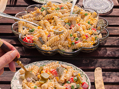 Spirellis mit buntem Gemüse und heller Sauce auf Tellern mit Dekoration.