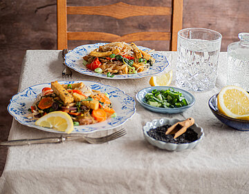 Glasnudelsalat mit buntem Gemüse und Tofustreifen auf Tellern mit Dekoration.