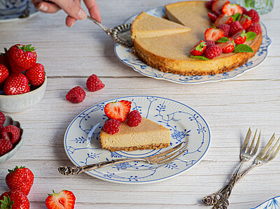 Käsekuchen auf zwei Tellern mit Erdbeerdekoration auf einem Tisch.