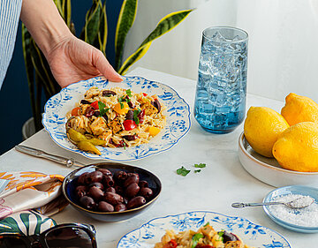 Pasta mit Tofuwürfeln und buntem Gemüse auf einem Teller mit Tischdekoration.