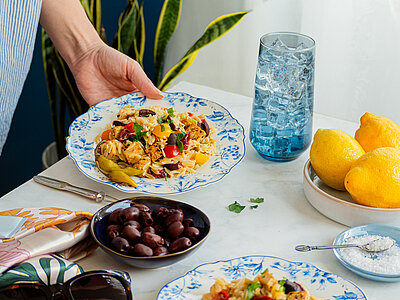 Pasta mit Tofuwürfeln und buntem Gemüse auf einem Teller mit Tischdekoration.