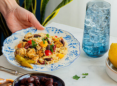 Pasta mit Tofuwürfeln und buntem Gemüse auf einem Teller mit Tischdekoration.