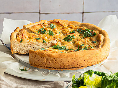 Zwiebelkuchen mit Tofu belegt, auf Tellern mit Tischdekoration.