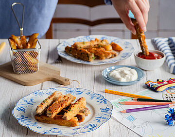  Panierte Tofu-Sticks auf Tellern mit Dip auf einem Tisch mit Dekoration.