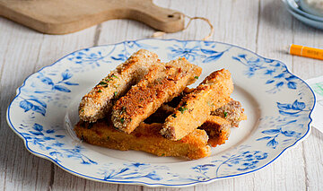  Panierte Tofu-Sticks auf Tellern mit Dip auf einem Tisch mit Dekoration.