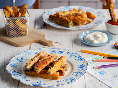  Panierte Tofu-Sticks auf Tellern mit Dip auf einem Tisch mit Dekoration.