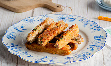  Panierte Tofu-Sticks auf Tellern mit Dip auf einem Tisch mit Dekoration.