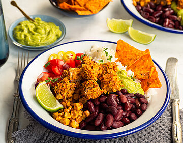 Panierte Tofu-Würfel mit Gemüse und Dip auf einem Teller und Tischdekoration.