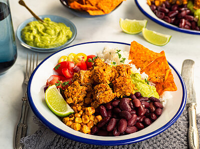 Panierte Tofu-Würfel mit Gemüse und Dip auf einem Teller und Tischdekoration.