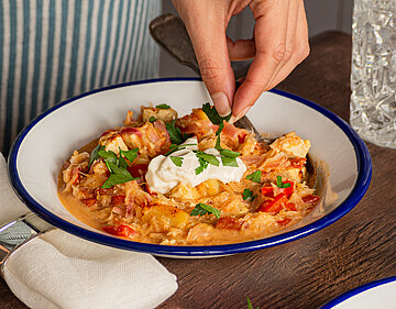 Tofu-Gulasch auf einem Teller mit Gemüse und Dip mit Tischdekoration.
