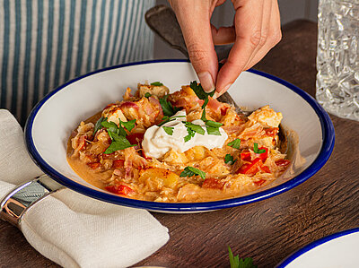 Tofu-Gulasch auf einem Teller mit Gemüse und Dip mit Tischdekoration.