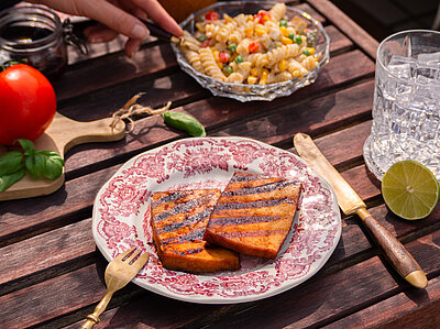 Tisch mit Tellern von Tofu, Nudeln, Oliven, Tomaten und Dekoration.