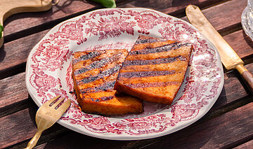 Tisch mit Tellern von Tofu, Nudeln, Oliven, Tomaten und Dekoration.
