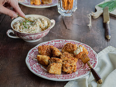 Tofu-Bretzel-Nuggets auf einem Teller auf einem Tisch mit einer Schüssel Obazda.