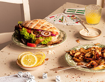 Fladenbrot auf Tellern mit Tofu, Salat und Zitronenscheiben mit Tischdekoration.