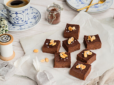 Erdnuss Brownies auf einer Tischdecke mit Dekoration.