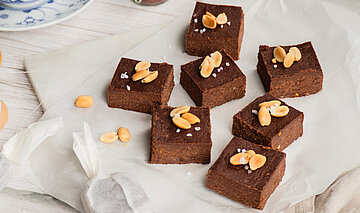 Erdnuss Brownies auf einer Tischdecke mit Dekoration.