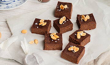 Erdnuss Brownies auf einer Tischdecke mit Dekoration.