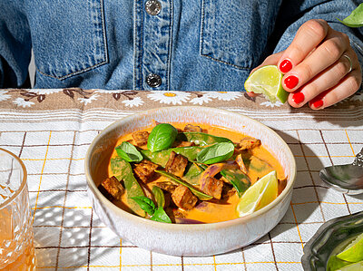 Eine Schüssel mit einem Curry auf einem Tischtuch mit Deko.