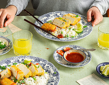 Aufgeschnittene Tofuscheibe auf Reis auf einem Teller mit Tischdekoration.