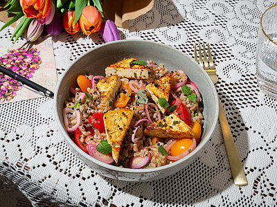 Bunter Salat mit Tofu auf einem Tischtuch mit Dekoration.