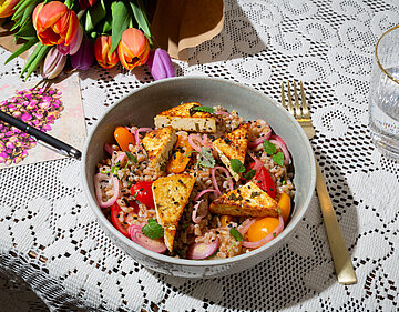 Bunter Salat mit Tofu auf einem Tischtuch mit Dekoration.