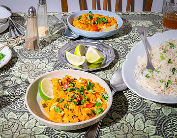 Linsen Dal Orangene Linsen auf Tellern dazu Reis Zitrone und Kräuter mit Dekoration.