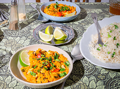 Orangene Linsen auf Tellern dazu Reis Zitrone und Kräuter mit Dekoration.