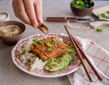 Tofuscheibe auf Reis mit Gurkenscheiben auf einem Teller mit Tischdekoration.