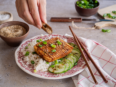 Tofuscheibe auf Reis mit Gurkenscheiben auf einem Teller mit Tischdekoration.