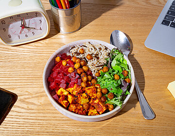 Tofuwürfel mit rote Bete Würfel, Kichererbsen und Salat an Reis in einer Schüssel mit Tischdekoration.