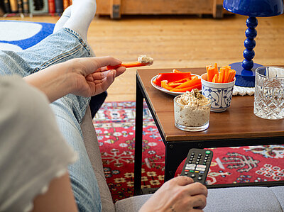 Helle Creme in einem Glas mit Möhrenstreifen und Tischdekoration.