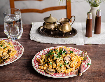 Spirellis mit Pilzen und Tofu auf einem Teller mit Dekoration.